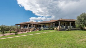 A two-story house with a stone facade, a red-tiled roof, and a covered porch. - Casa Pompia 3 (Siniscola)
