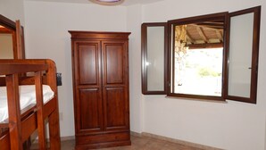 A room with a wooden wardrobe, a bed, and a window with a view of the outside. - Casa Pompia 3 (Siniscola)