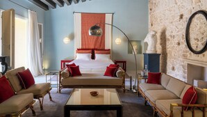 Een hotelkamer met een groot bed, twee banken, een salontafel en een stenen muur.