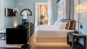 Een moderne hotelkamer met een bed, een bureau, een stoel en een groot raam met uitzicht op een buitenbalkon.