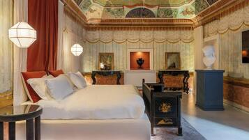Un dormitorio lujoso con una cama grande, un techo ornamentado y una decoración clásica.