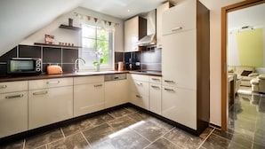 A modern kitchen with a built-in oven, microwave, and toaster. It features a window with a view of greenery outside.