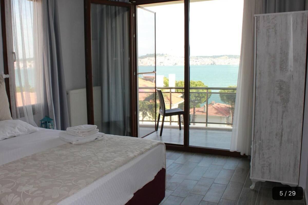 A hotel room with a bed, a chair, and a view of the sea.