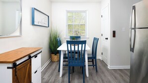 Une cuisine avec un réfrigérateur blanc, un comptoir en bois et une table à manger entourée de chaises bleues.