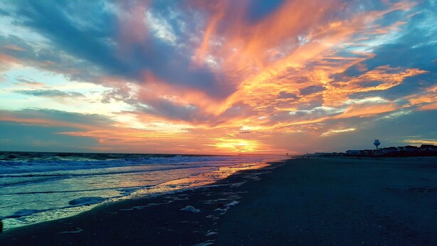 A beach with a sunset, waves, and a pier in the distance. - Spectacular Sunset Views  from this Top/3rd floor condo, 2 bed/2 bath (Ocean Isle Beach)