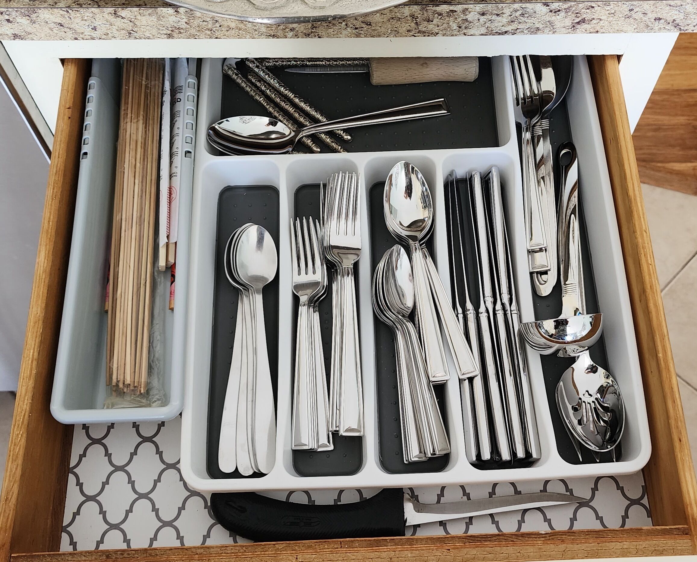 A drawer with neatly organized silverware, including forks, spoons, and knives.