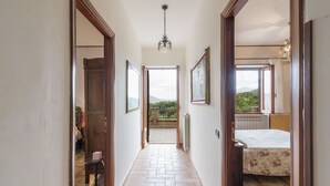 A hallway with a tiled floor leading to a bedroom with a bed and a window. There are framed pictures on the walls and a chandelier hanging from the ceiling. - Wonderful private villa for 6 people with private pool, WIFI, TV, terrace and pets allowed (Santa Maria)