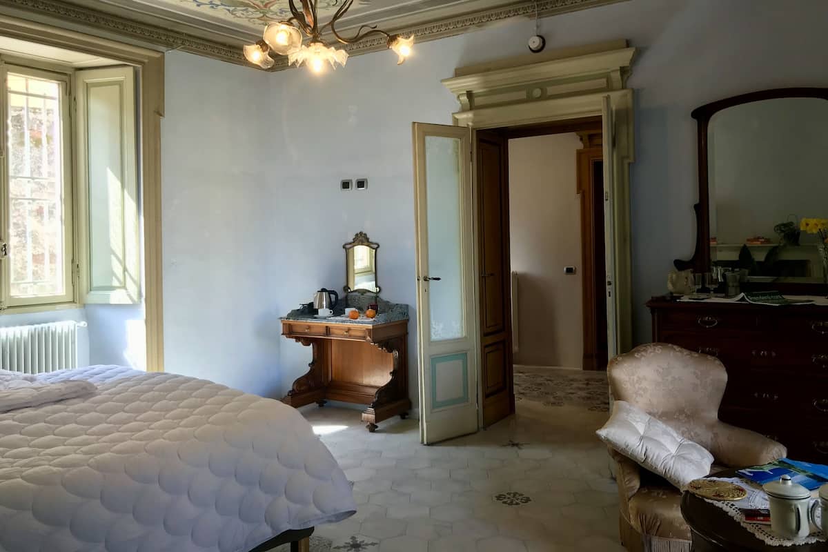 A room with a bed, a dresser, a chair, and a mirror.