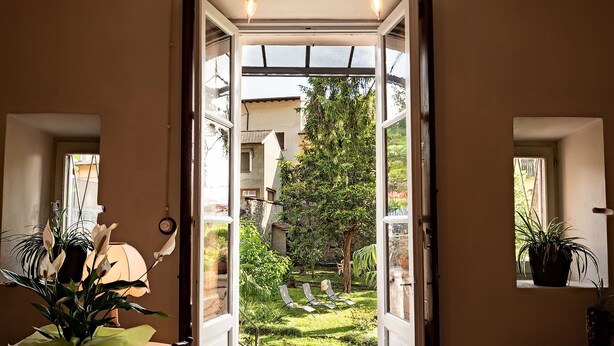 Puerta abierta que da a un jardín con vistas a un árbol y una casa.