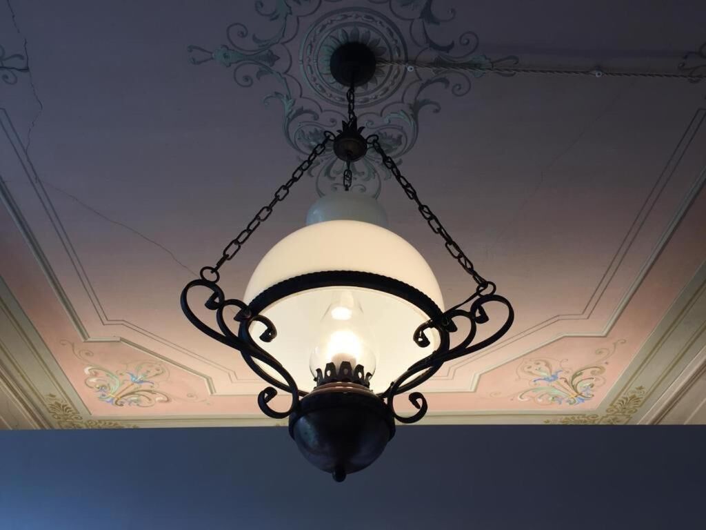 Een kroonluchter met een heldere glazen lamp, hangend aan een zwarte metalen fitting.