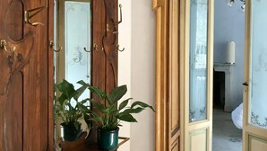 Un pasillo con un marco de puerta de madera, un espejo y una planta en maceta.