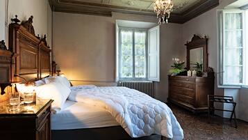Un dormitorio con una cama grande, un aparador, un espejo y un ventanal con vistas a árboles.