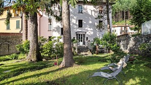 Un patio con un edificio blanco, una pared de piedra y una zona de estar con dos sillas.
