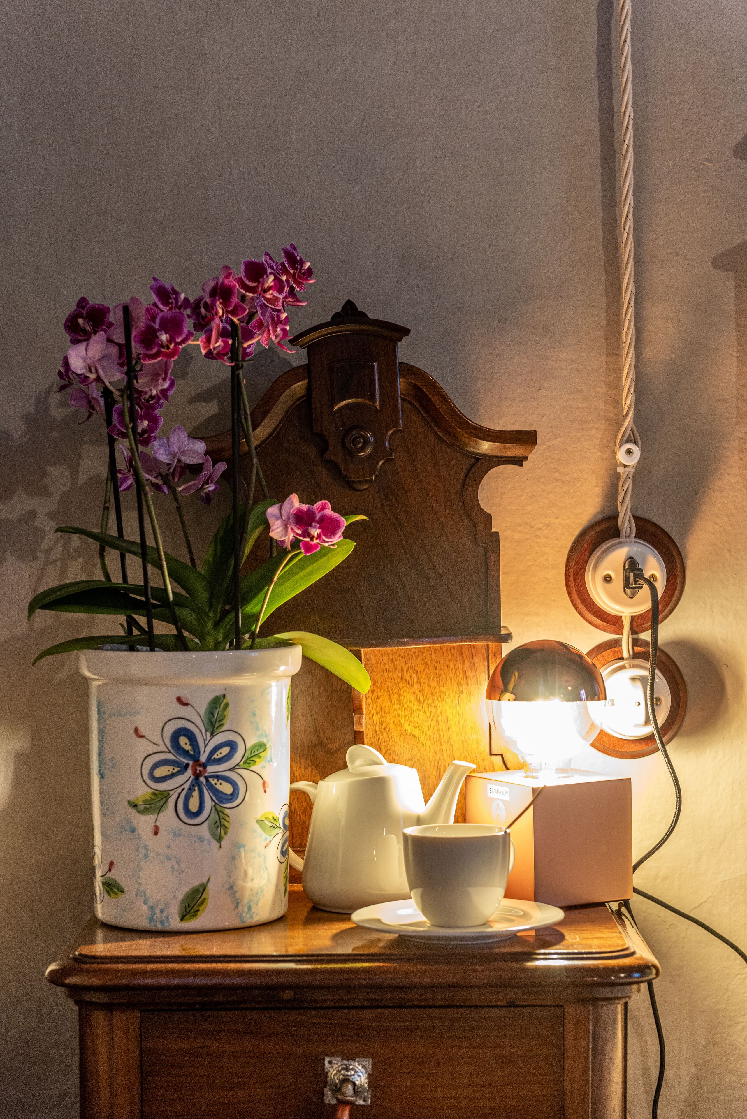 A wooden table with a floral vase, a teapot, a cup, and a box.