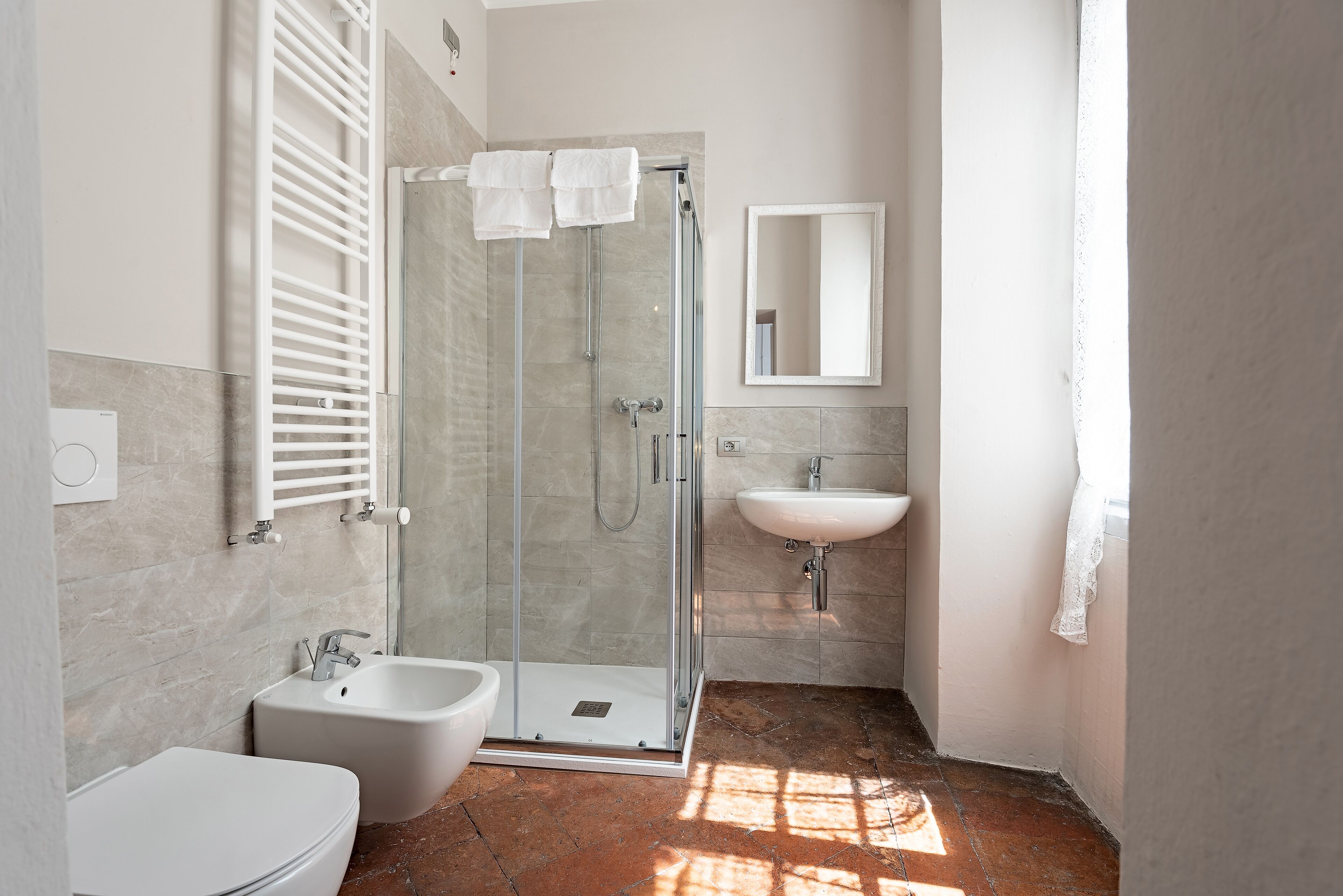 A modern bathroom with a glass-enclosed shower, a white sink, and a bidet.