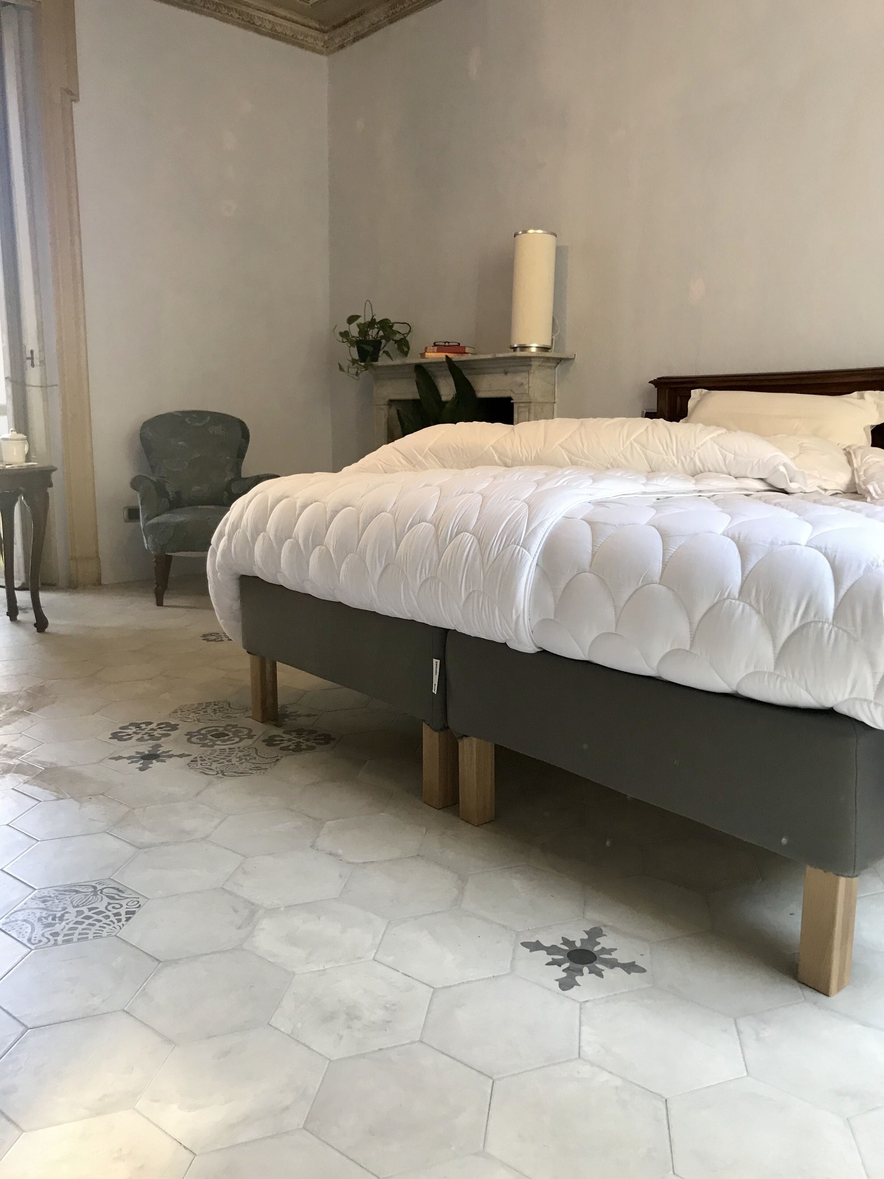 Un dormitorio con una cama grande, una silla, una chimenea y una mesita.