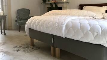 Un dormitorio con una cama grande, una silla, una chimenea y una mesita.