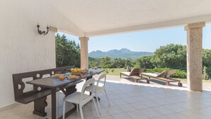Un porche techado con una mesa de comedor, sillas y vistas a las montañas.
