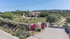 Un camino de piedra que lleva a una casa con jardín y vistas del paisaje circundante.