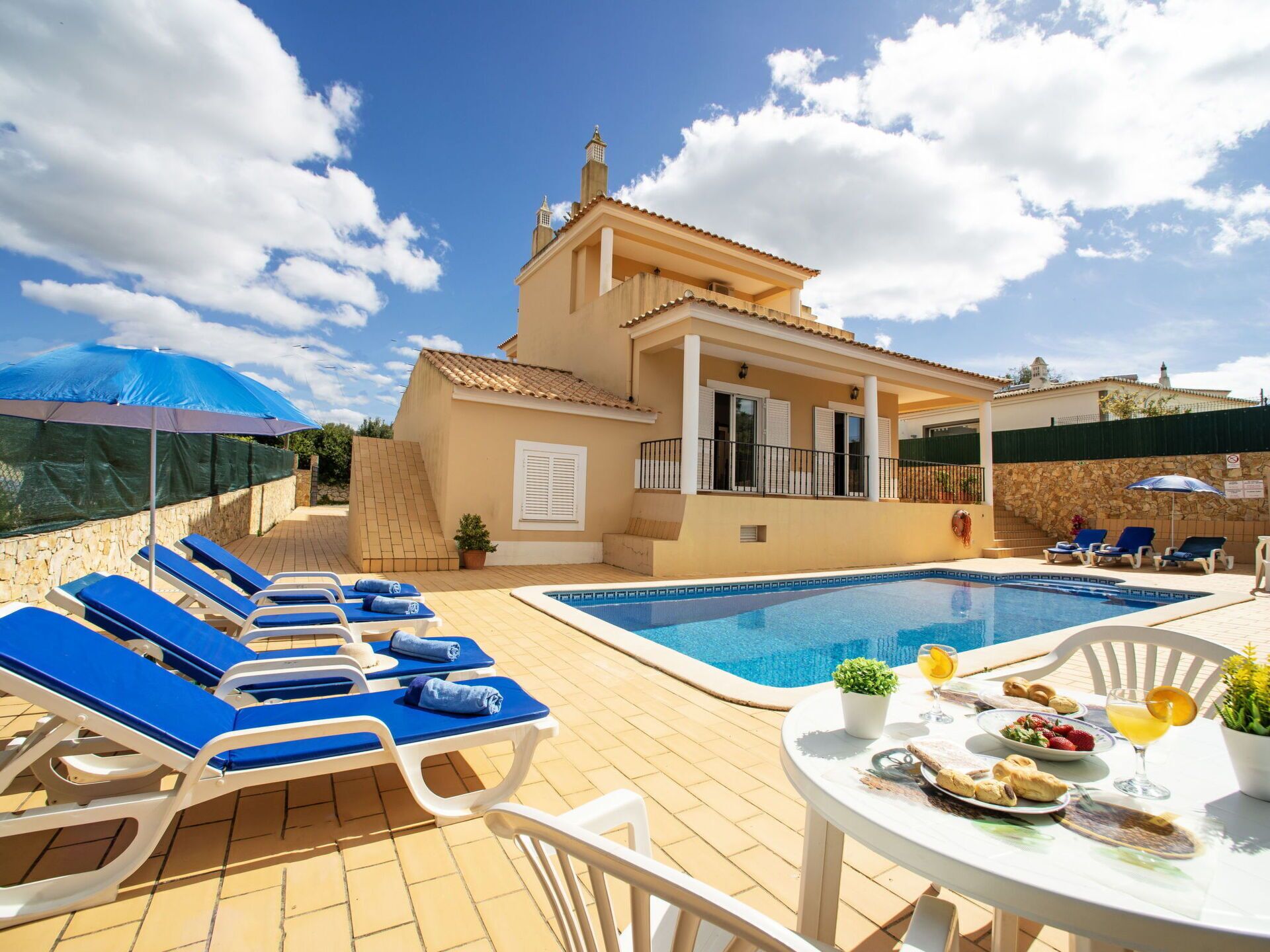 A poolside area with lounge chairs and a table set for a meal.