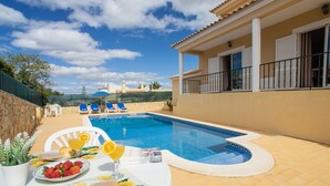 Une piscine avec un transat et une table où sont servis des plats et des boissons.