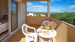 Un balcon avec une table préparée pour le petit-déjeuner, une chaise et une vue sur le paysage.