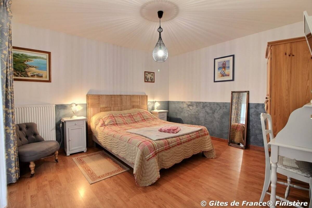 A bedroom with a wooden bed, bedside lamps, a chair, a mirror, and a radiator.