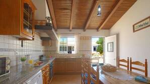 Une cuisine dotée de meubles en bois, d’un lave-vaisselle encastré et d’un coin repas avec une table et des chaises en bois.