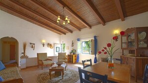 Un salon chaleureux avec un plafond en bois, une table à manger, des chaises et un lustre.