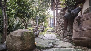 A stone pathway in a garden with large rocks and potted plants. - Bella Vita Style rooms & apartments-Incanto (Pitsidia)