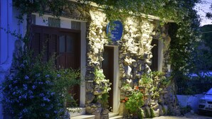 A stone facade with a sign, a door, and steps leading to a building entrance. - Bella Vita Style rooms & apartments-Incanto (Pitsidia)