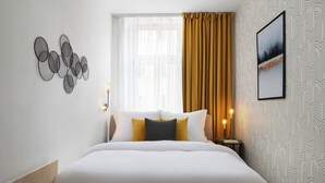A neatly arranged hotel room with a large bed, a side table with a lamp, and a wall-mounted picture. - Apartment Pekarska 29 by goodnite cz (Brno)