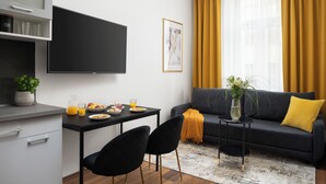 A modern living room with a black sofa, a small black table, and a dining area with a black table and chairs. - Apartment Pekarska 29 by goodnite cz (Brno)