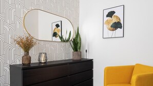 A modern living room with a dark wooden dresser, a yellow armchair, a large mirror, and a framed abstract painting. - Apartment Pekarska 29 by goodnite cz (Brno)