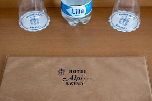 A brown leather folder with the Hotel Alpi Baveno logo and a bottle of Lilia water. - Alpi (Baveno)