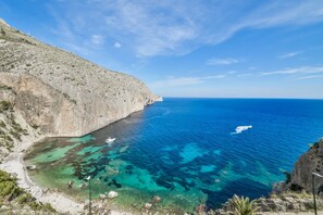 A coastal landscape with clear turquoise waters, rocky cliffs, and a boat in the distance. - Sea front apartment in Altea, Pueblo Mascarat, Ref 1045 Elena Hills (Altea)