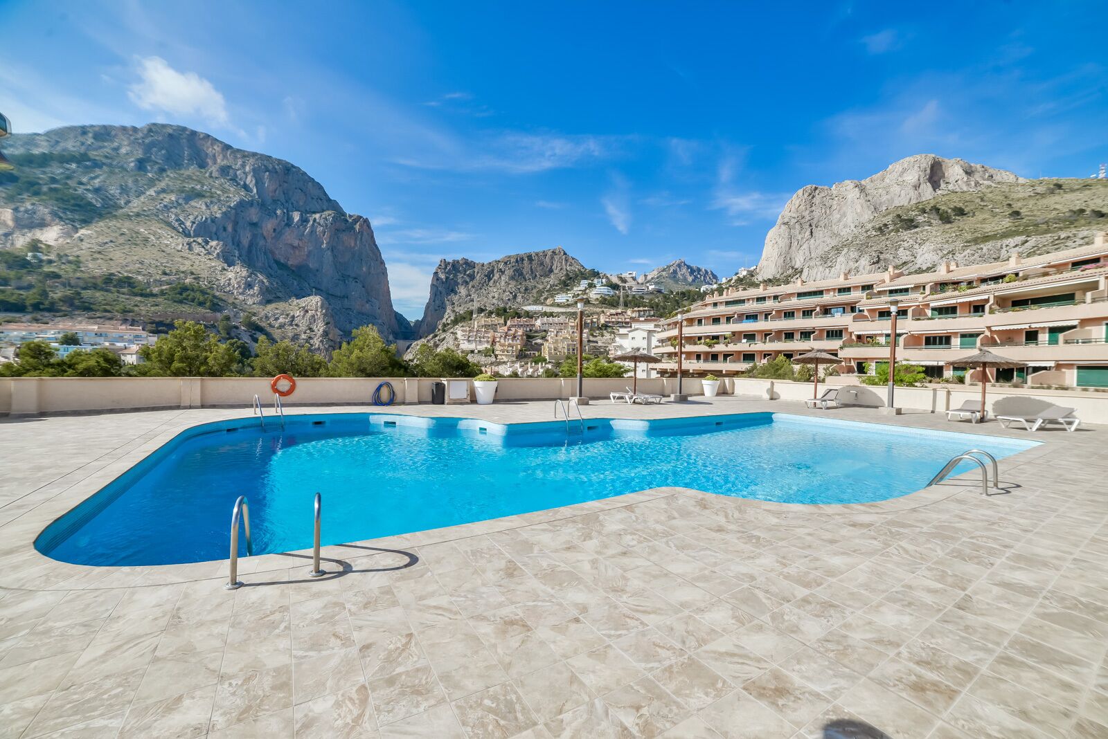 Ein Pool mit Bergblick und einem Hotel im Hintergrund.