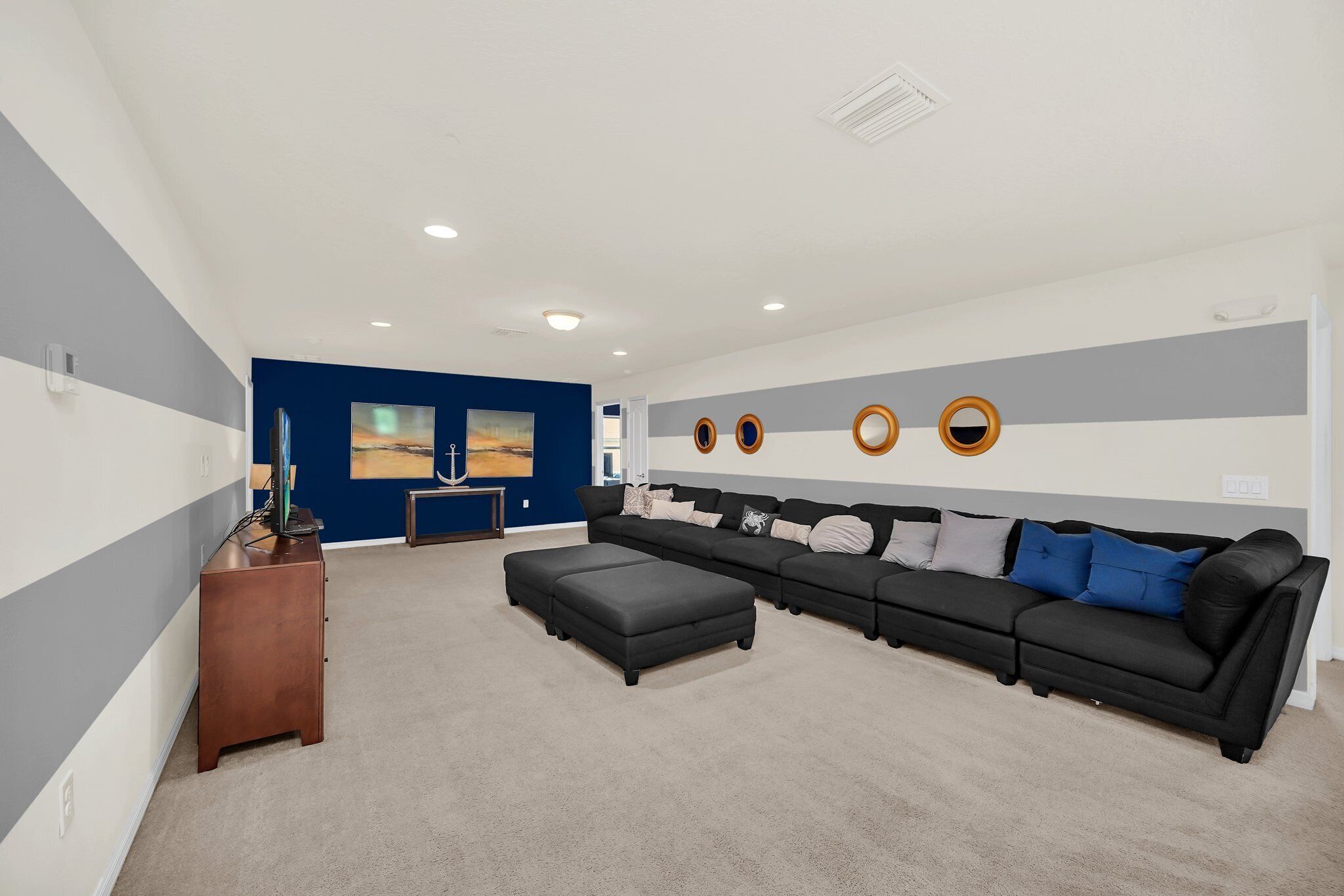 A modern living room with a sectional sofa, ottoman, and a wooden cabinet.
