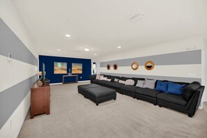 A modern living room with a sectional sofa, ottoman, and a wooden cabinet.