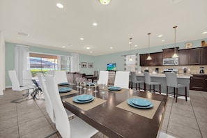 A modern dining area with a dark wooden table, white chairs, and blue plates.
