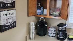 A kitchen with a coffee maker, a kettle, a coffee grinder, and a cabinet containing coffee products. - Great Home; Close to Everywhere. (Oak Grove)