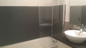 A bathroom with a bathtub, a sink, and a shower enclosure.
