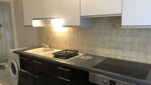 A kitchen with a sink, black cabinets, a dishwasher, and a stove.