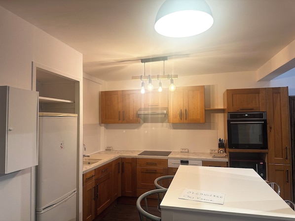 A modern kitchen with wooden cabinets, a built-in oven, and a white countertop.