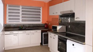 A compact kitchen with white cabinets, a microwave, a dishwasher, and a small refrigerator. - Apartment near Basel / Mulhouse Airport (Saint-Louis)
