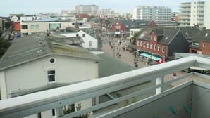 Un paysage urbain mêlant bâtiments modernes et traditionnels, une rue piétonne et une vue sur le front de mer.