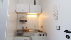 Une petite cuisine équipée comprenant une cuisinière, un évier et des placards de rangement.