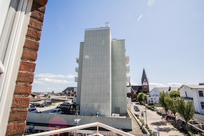 Een modern gebouw met een glazen gevel, omringd door andere gebouwen en een heldere lucht.