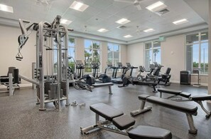 A gym with various exercise equipment, including treadmills, weight machines, and benches.
