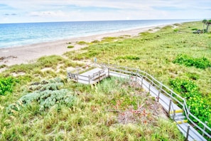 Un sentier côtier avec un pont en bois menant à une plage.
